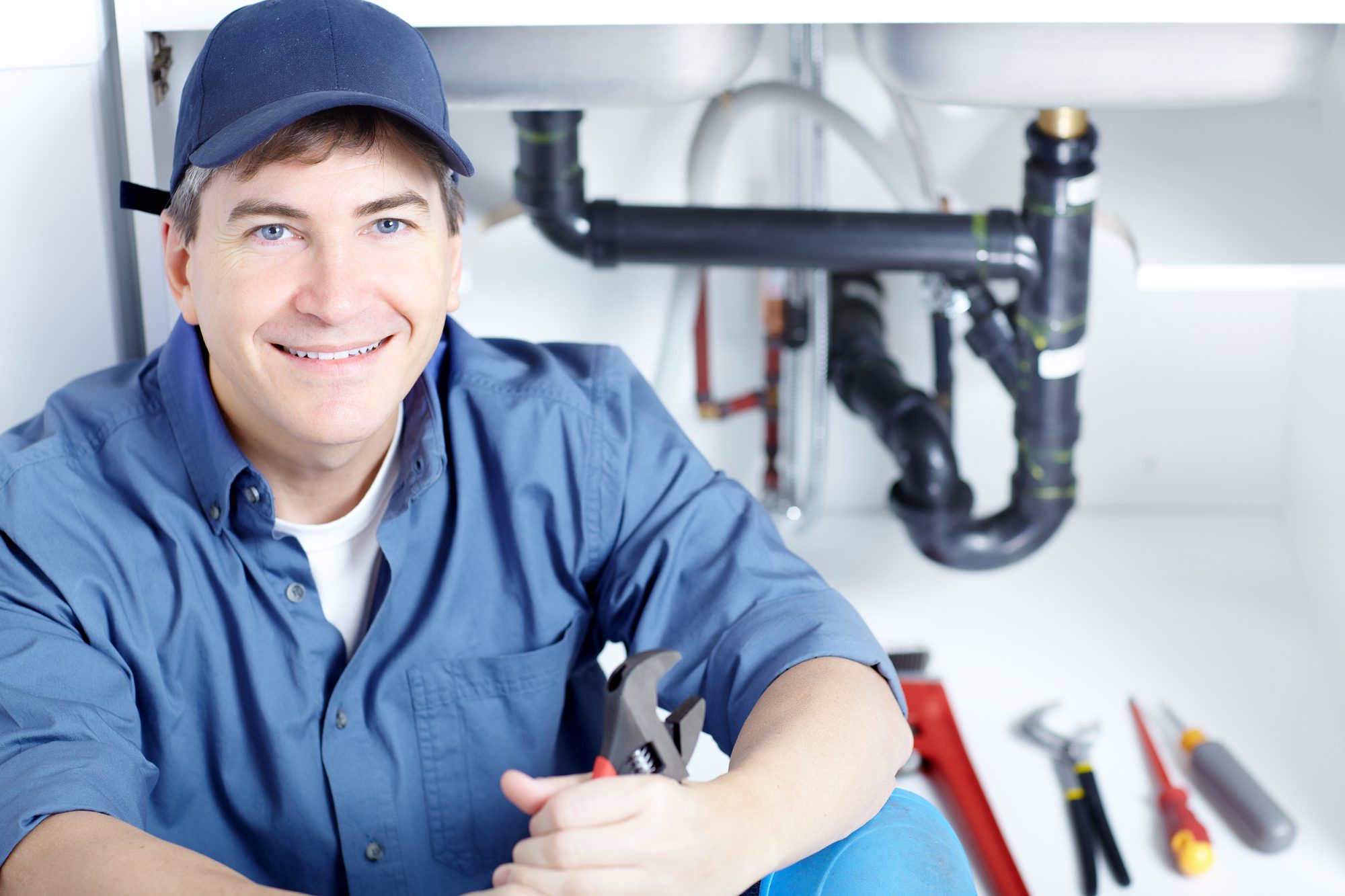 Male plumber fixing a sink at kitchen